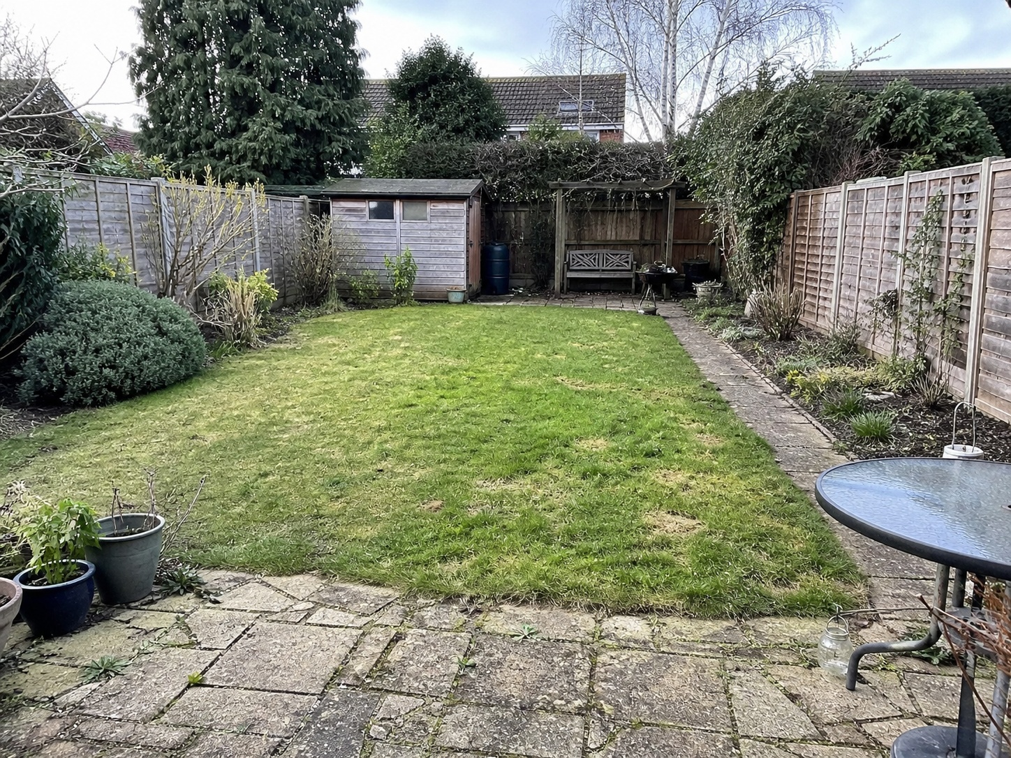 Worn paving and patchy grass before landscaping, used as a before image in an AI mock-up